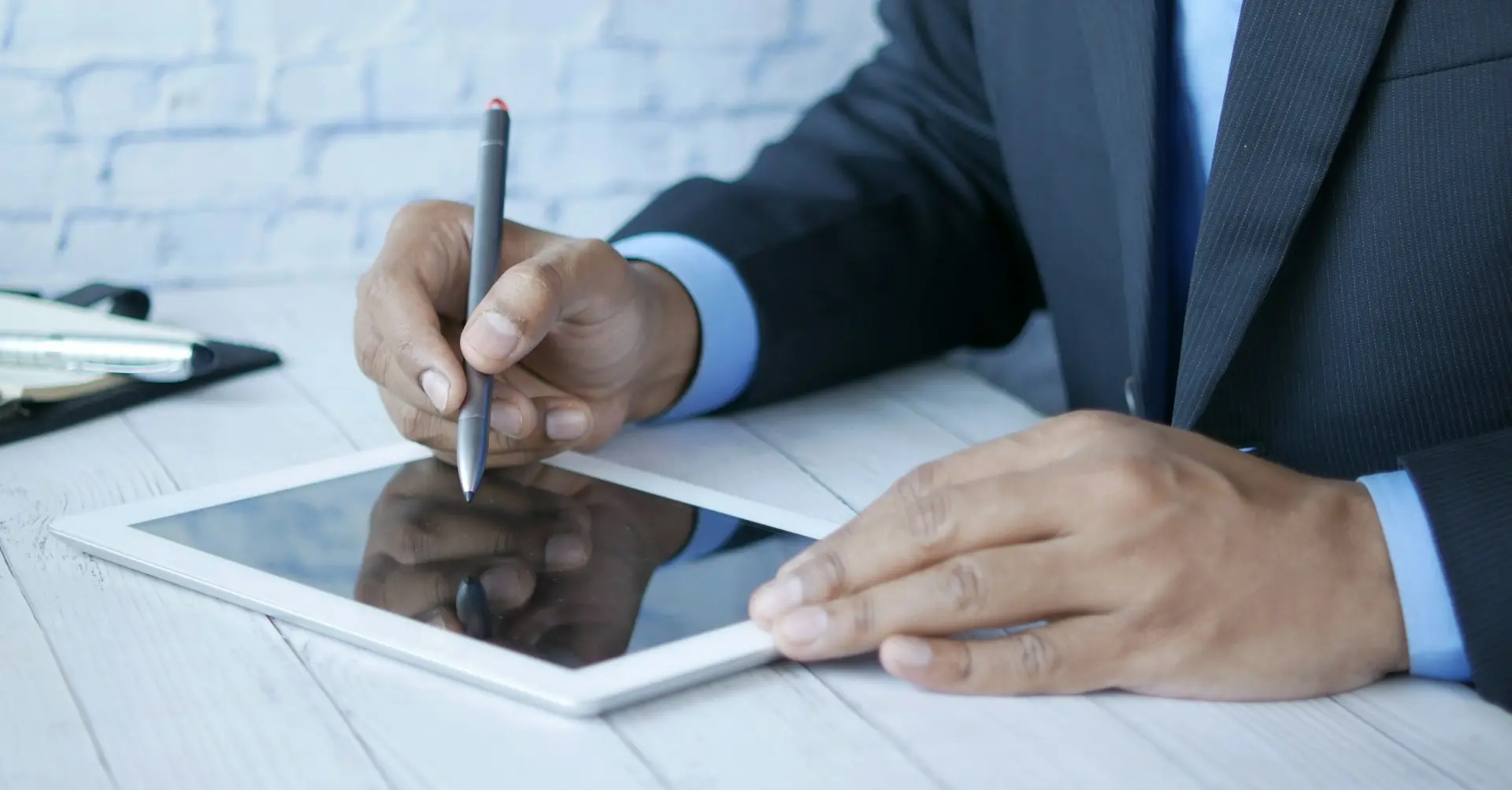 a man in a suit writing on a tablet