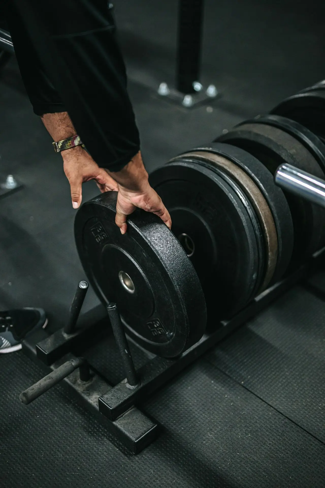 person holding black dumbbell in black gym