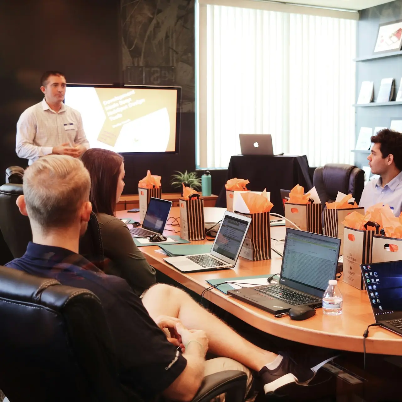 man standing in front of people sitting beside table with laptop computers